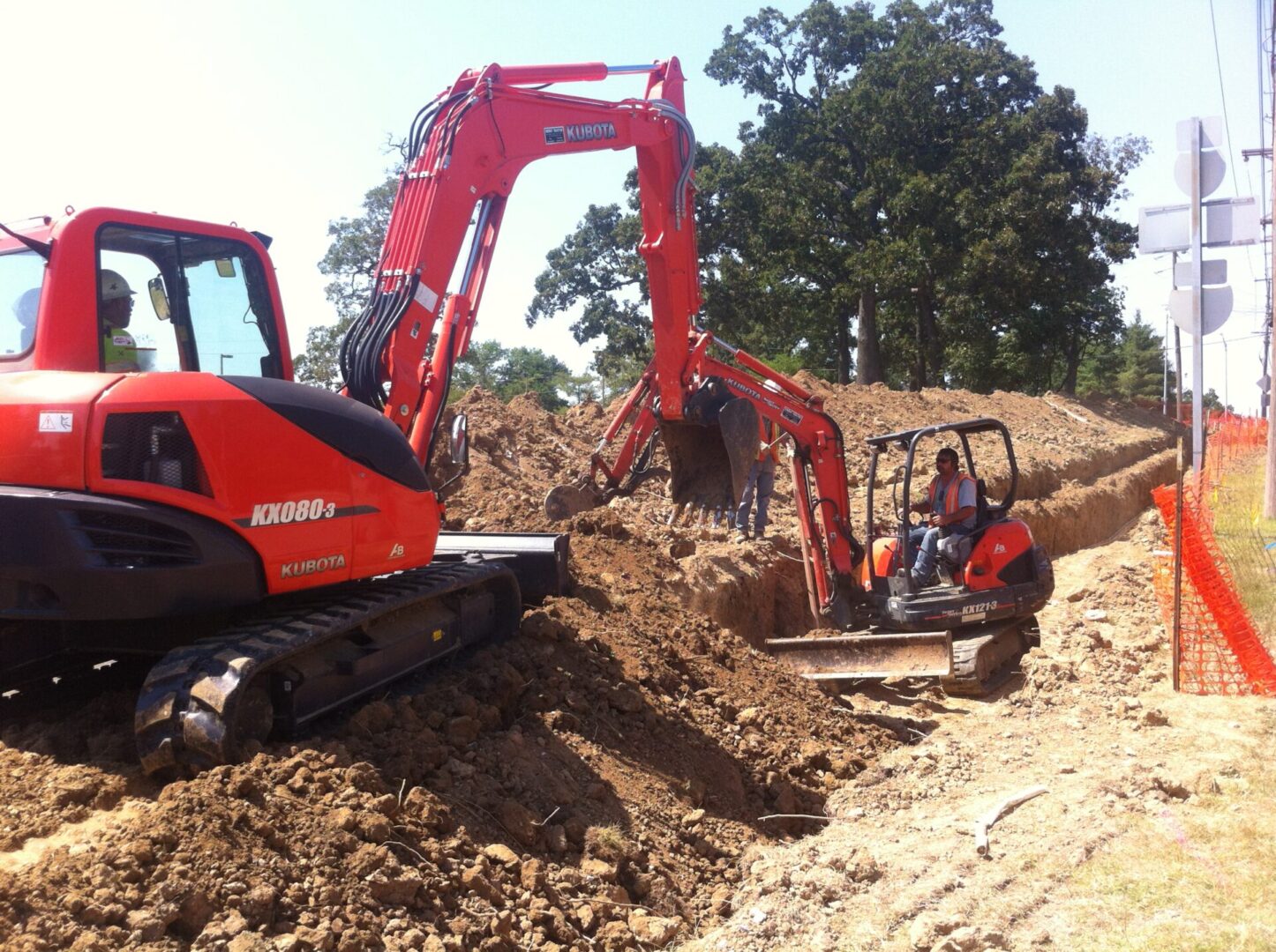 A red tractor is digging in the dirt