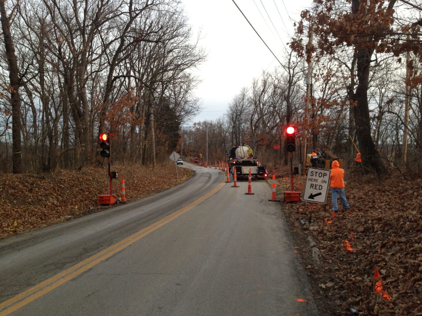 A road with construction signs and trees